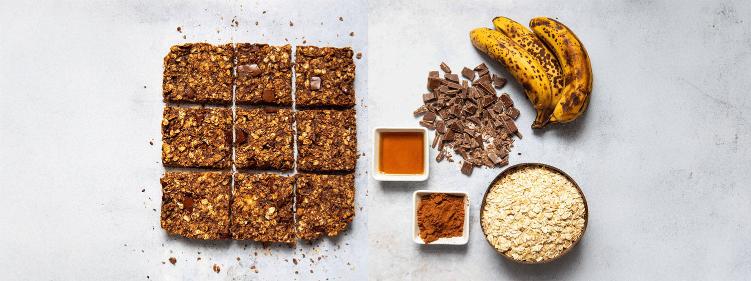 Homemade vegan chocolate oat slices cut into squares, displayed with ingredients including ripe bananas, chopped dark chocolate, oats, maple syrup, and cacao powder.