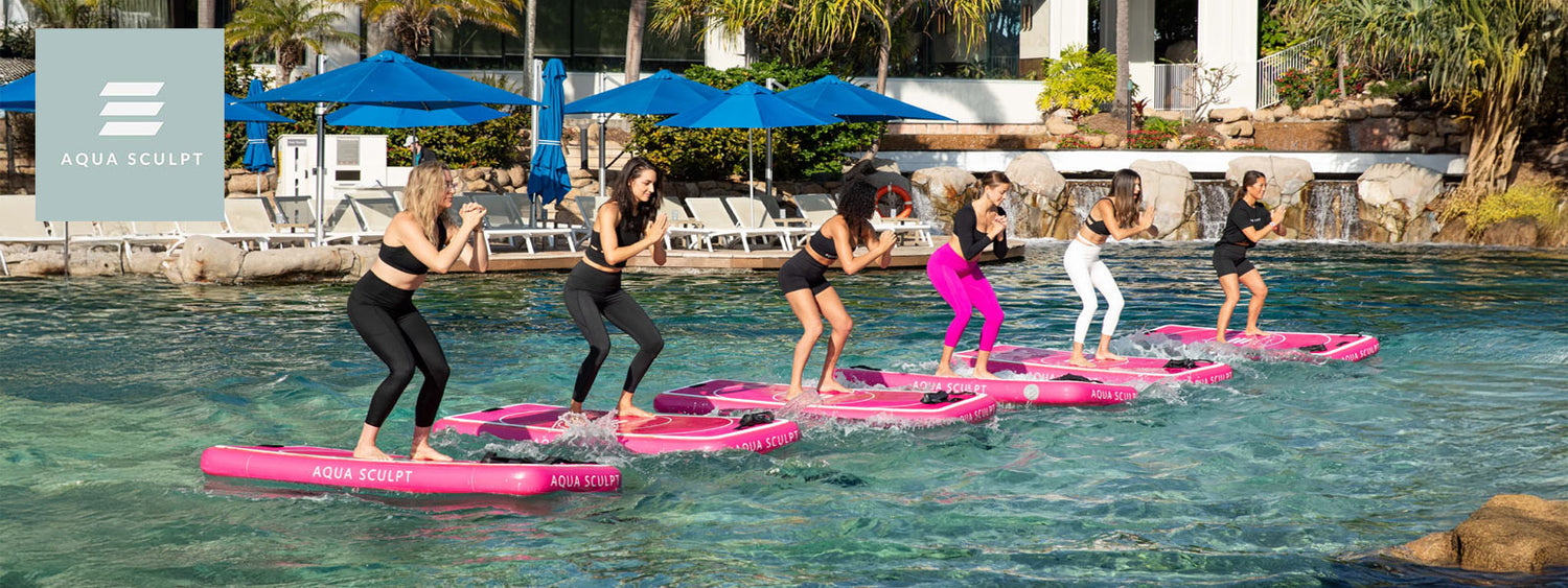 Group of women balancing on Aqua Sculpt floating boards during a Pilates class at JW Marriott Gold Coast lagoon pool.