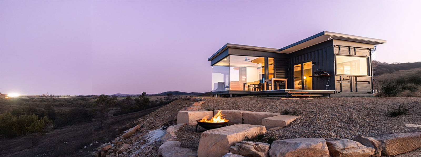 Modern eco-lodge with firepit overlooking the hills at sunset, at Sierra Escape glamping retreat in Mudgee NSW