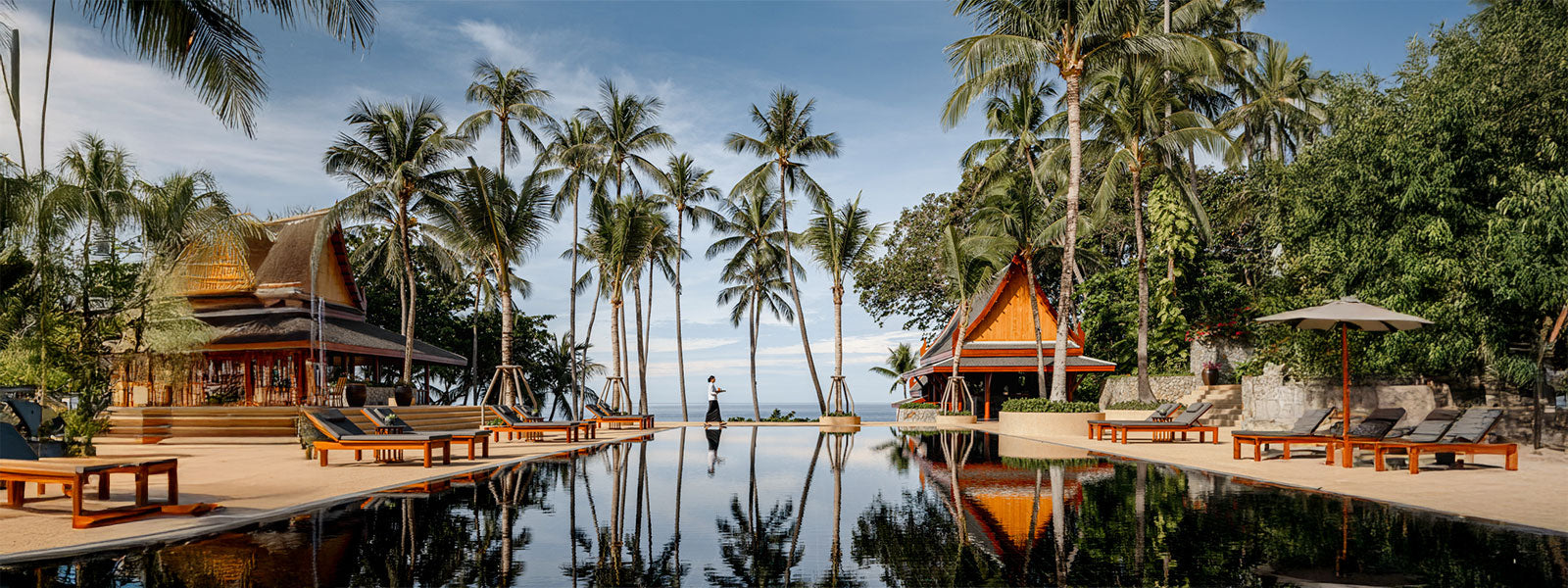 Amanpuri Phuket beachfront villas and reflection pool lined with palm trees and traditional Thai architecture