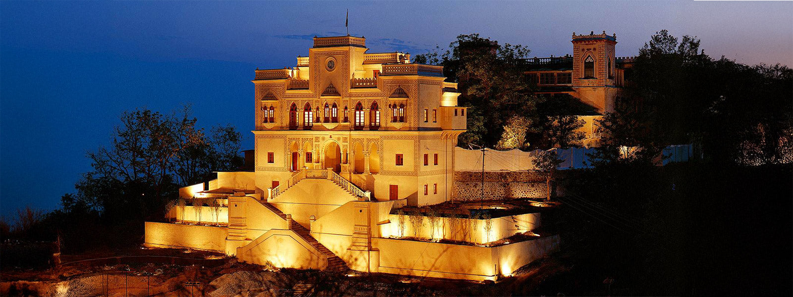 Ananda in the Himalayas luxury wellness retreat lit up at night, nestled in the Himalayan foothills of India
