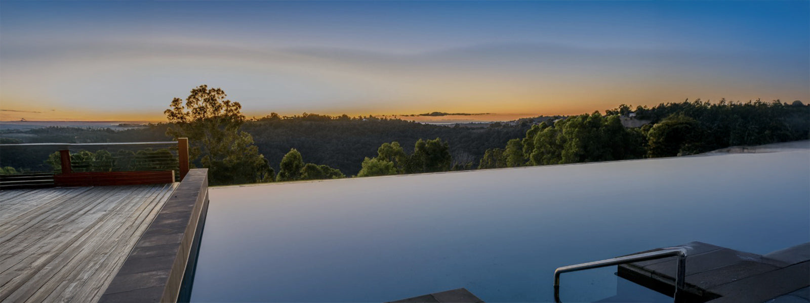 Infinity pool at Gwinganna Lifestyle Retreat overlooking the Tallebudgera Valley hinterland at sunrise, with panoramic views stretching to the Gold Coast coastline