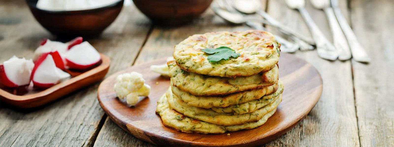 Stack of homemade Mexican cauliflower tortillas on a wooden plate, low-carb paleo keto vegan gluten-free wraps made with organic cauliflower.