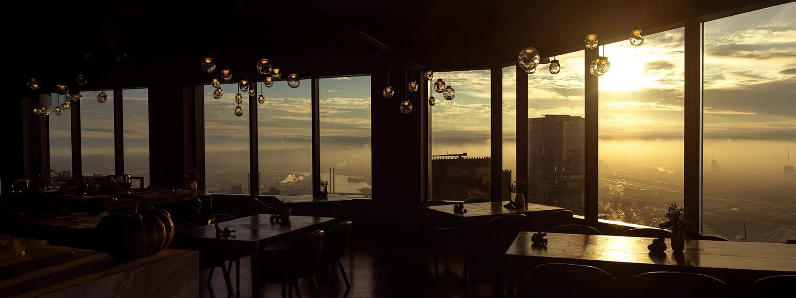 Vue de monde restaurant interior at Rialto Tower with sunset skyline views over Melbourne, fine dining tables and pendant lighting creating a dramatic city dining scene.