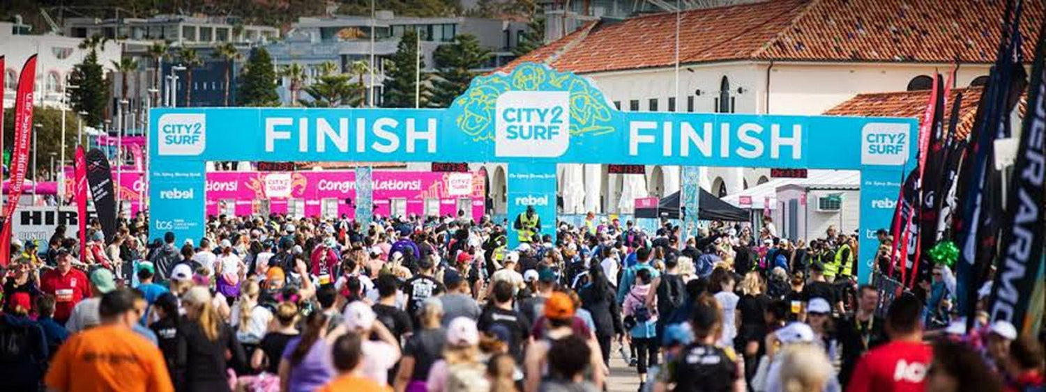 City2Surf 2025 afterparty crowd at Bondi Beach under branded banners